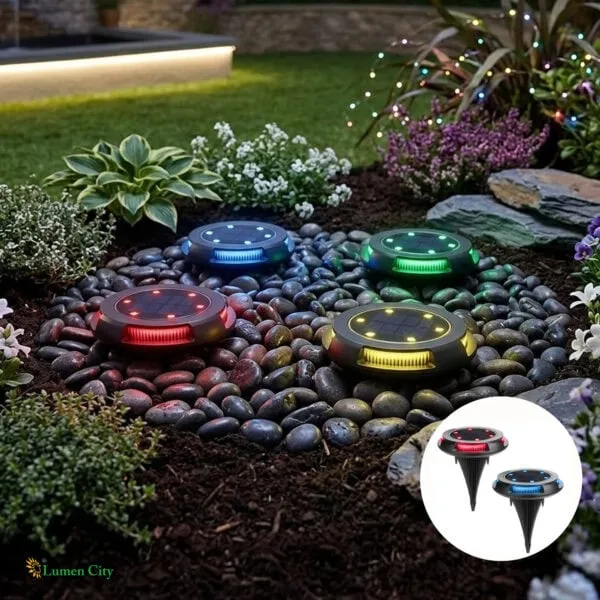 LED garden lights with colorful illumination on decorative stones in a landscaped outdoor setting.